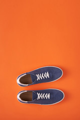 Top view of casual blue suede sneakers on orange background