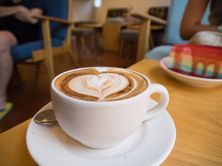 Hot latte art coffee in white cup on wood table