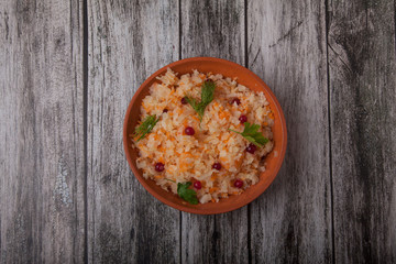 salad of fermented cabbage and cranberries with herbs stands in a clay cup on a wooden brown table
