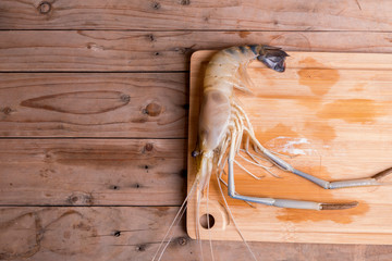 Big prawns on the wooden chopping board on the wooden table