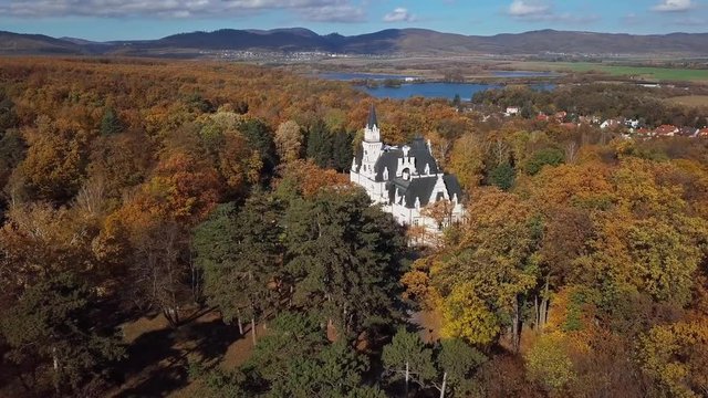 Flight over Budmerice Castle in autumn forest, Slovakia.