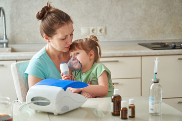 woman makes inhalation to a child at home. brings the nebulizer mask to his face. inhales the vapor...