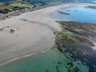 Fototapeta na wymiar Aerial view of wonderful beach with white sand and turquoise water, with some rocks underwater and few people swimming. Aerial view South coast of Guernsey island, UK, Europe.