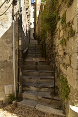 Fototapeta na wymiar Escaliers étroits et ombragé entre deux vieux murs en pierres dans le quartier médiéval de Périgueux en Dordogne