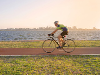 Blurred young man cycling on bike lane along the river