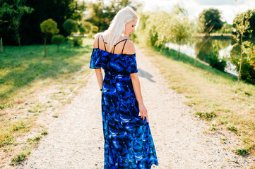 Beautiful blonde girl posing at nature in blue dress