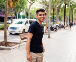 Young fashionable handsome man on the street of modern city. He looks happy