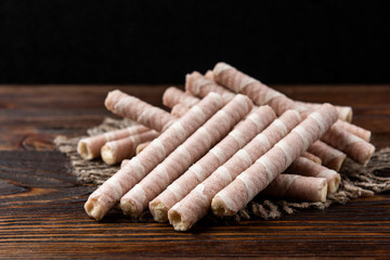 Sweet chocolate waffle rolls on dark wooden background.