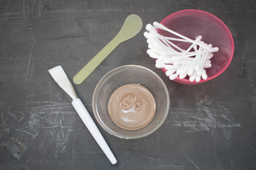 bowl with cosmetic dirt, skin care kit ha, brush, cotton buds on a dark background