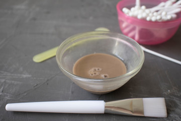 bowl with cosmetic dirt, skin care kit ha, brush, cotton buds on a dark background