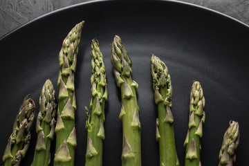 Green fresh asparagus on black black plate