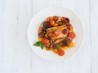 vista desde arriba plato blanco sobre madera blanca con salmon y tomates cherrie