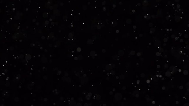 Microscopic dust pieces falling from top to bottom. Slow motion