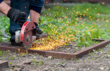Hand of man with steel cutter tool on green background. Worker outside, cut the metal rails....