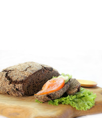 Rye bread with salad leaves and tomato on a cutting Board with free space for text.