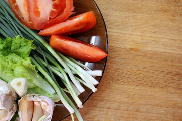 Plate with tomato, garlic and herbs on a wooden Board background.