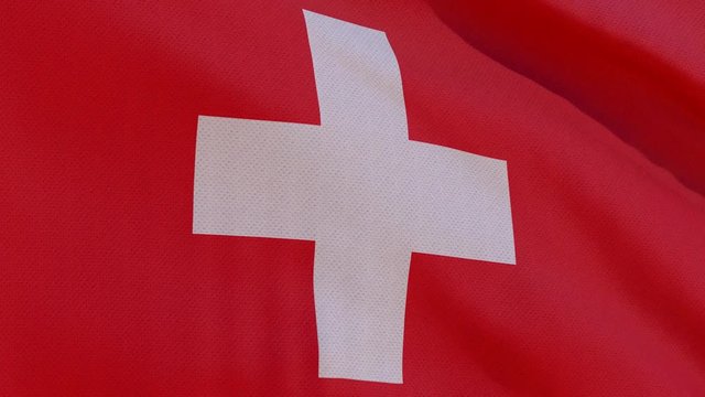 This stock motion graphics video shows the national flag of Switzerland with its white cross over a red background, waving in slow motion. 4k seamless loop