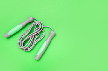 Jump rope on green background, top view