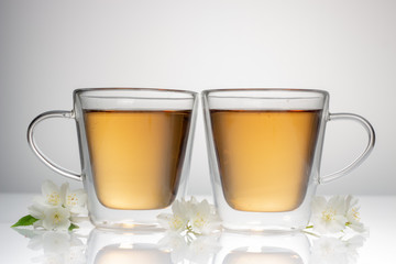 green tea with jasmine in a transparent glass thermomug on a white background