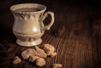 Vintage cup of coffee with pieces of brown sugar and coffee beans 