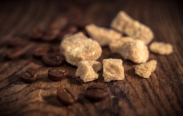 Pieces of brown sugar and coffee beans on rustic wooden table