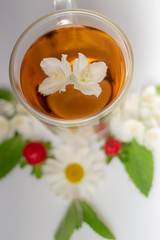 green tea with jasmine in a transparent glass thermomug on a white background
