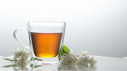 green tea with jasmine in a transparent glass thermomug on a white background