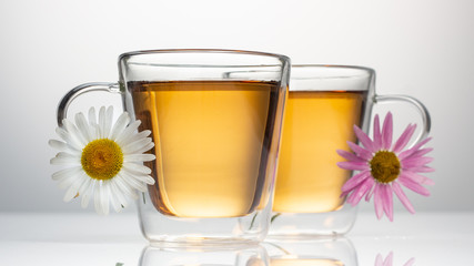 cup of herbal tea with chamomile flowers on a white table