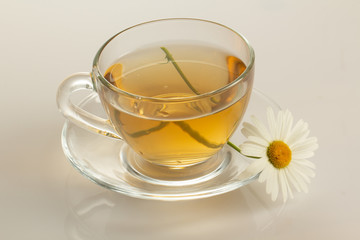 cup of herbal tea with chamomile flowers on a white table