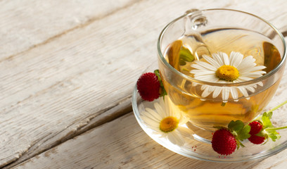 cup of herbal tea with chamomile flowers on a white table