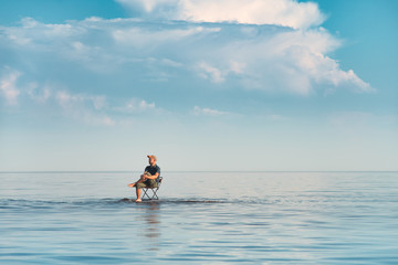 A man sits on a chair in the water