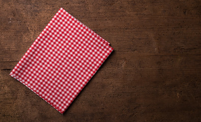 Empty wooden deck table and red checked tablecloth over mint wallpaper background