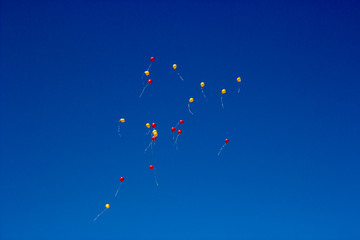 yellow and red balloons fly into the blue sky
