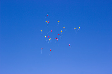 yellow and red balloons fly into the blue sky