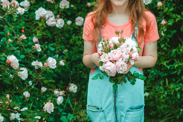 gardener girl collected a bouquet of pink on a background of rose bushes