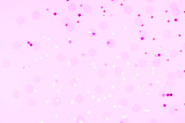 Pink confetti and stars and sparkles on pink background. Top view, flat lay. Copyspace for text. Bright and festive holiday background. For Christmas, New year, Mother's day.