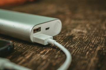 Charging the empty battery smartphone with power bank on wooden background 