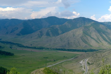 Fototapeta premium Mountain landscape. At the foot of the mountains, plain and the road with cars
