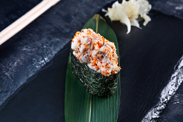 Close up view on gunkan sushi with spicy sauce and eel on dark stone background. Fresh Japanese...