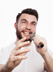 young bearded man in white shirt singing in microphone