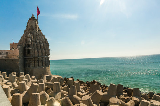 Lone hindu temple with flag on arabian sea coast with wave breakers