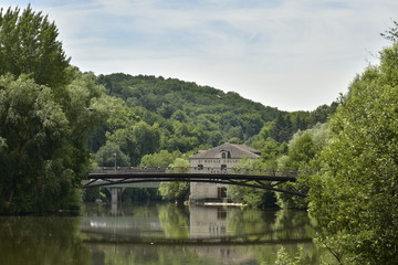 Fototapeta premium Reflet parfait du pont métallique et d'un bâtiment historique dans l'Isle au fond d'une vallée verdoyante en aval de Périgueux en Dordogne