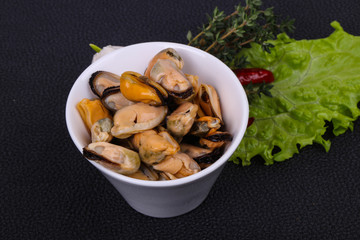 Pickled mussels in the bowl served pepper, garlic and salad