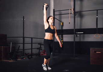 Fototapeta na wymiar Young woman realizing indoor exercises with kettlebell