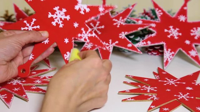Woman painting winter holiday decorations. Closeup view of female hands and wooden toys. Blogger making video about how to make christmas toy with your own hands.