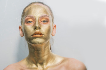 gold make-up face mask, closeup healthy young woman gold