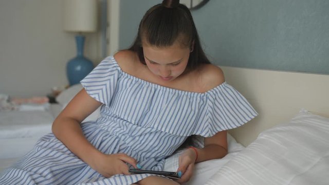 Girl teenager lying on the bed and use the tablet. Adolescence.