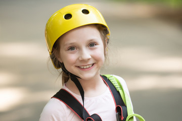 Children summer activities. Toddler age. Safe Climbing extreme sport with helmet. Active children. Portrait of a beautiful kid on a rope park among trees.