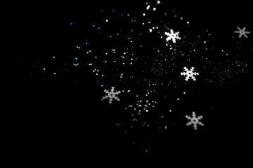 Abstract black background with isolated defocused snowflakes.