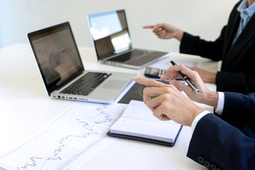 business man and woman sit at ther table looking at computer laptop